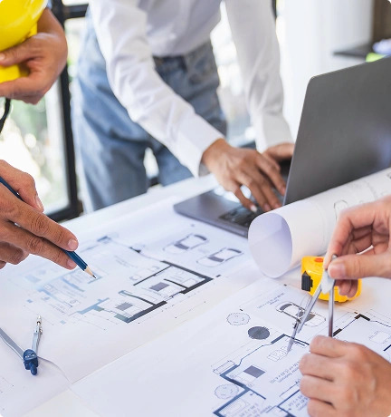 A diverse group of people collaborating on a project at a table, with laptops and documents spread out